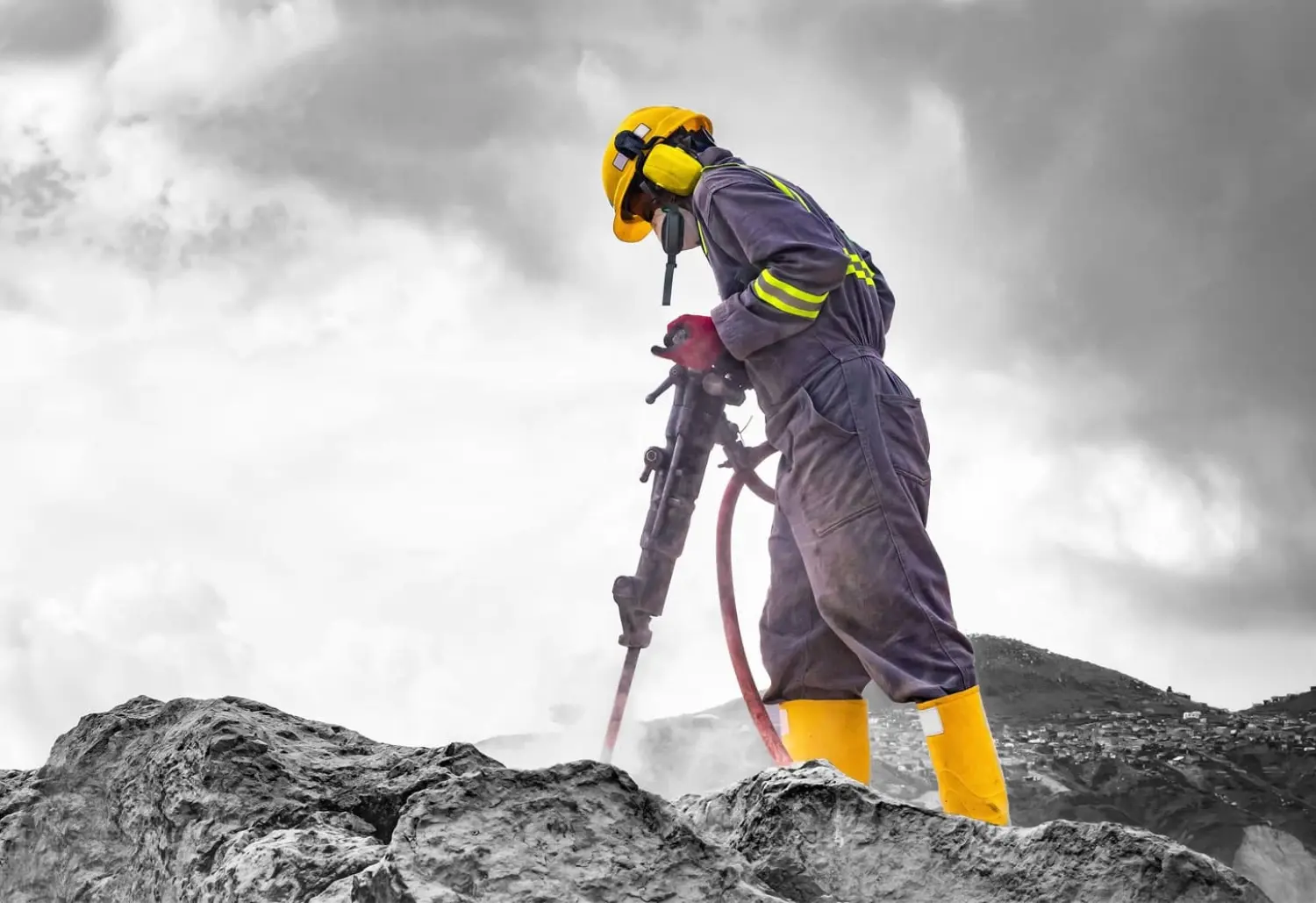 Worker drilling with a pneumatic drill and hearing protection.