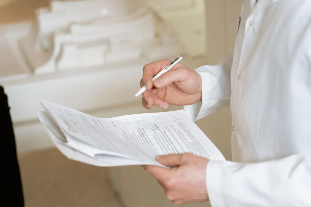 Healthcare worker evaluating a patient while holding a clipboard containing papers with a checklist.