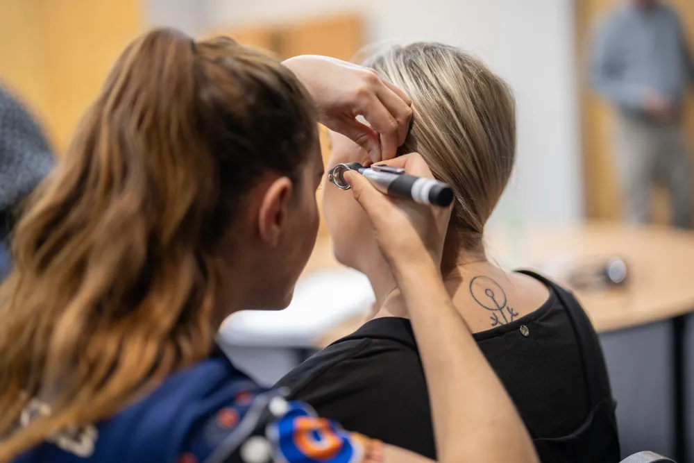 Participant using an otoscope to inspect someone's ear