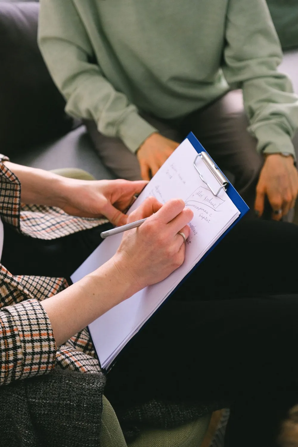 Healthcare worker evaluating a patient while writing on a clipboard.
