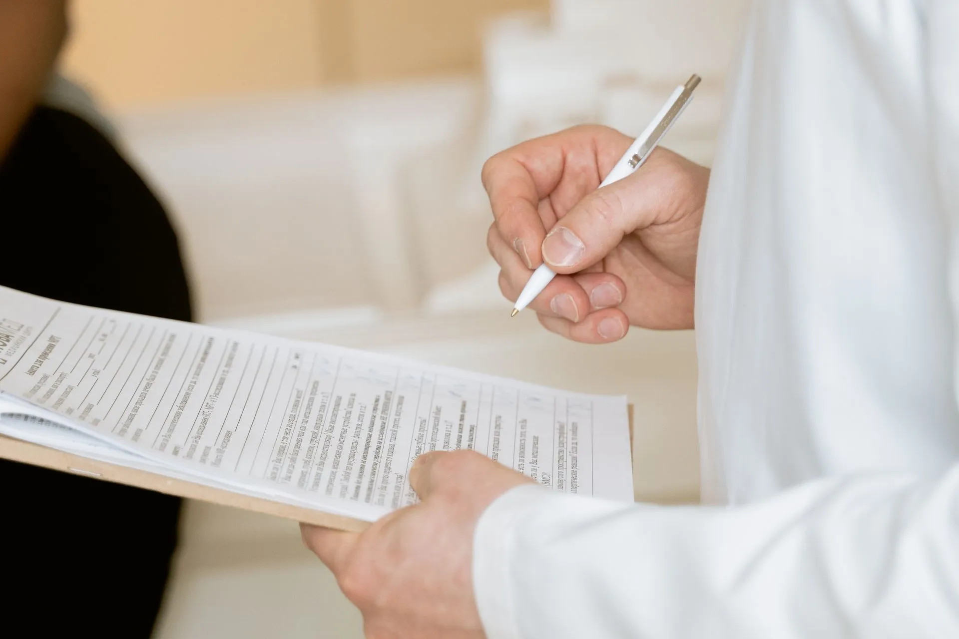 Healthcare worker evaluating a patient while holding a clipboard containing papers with a checklist.